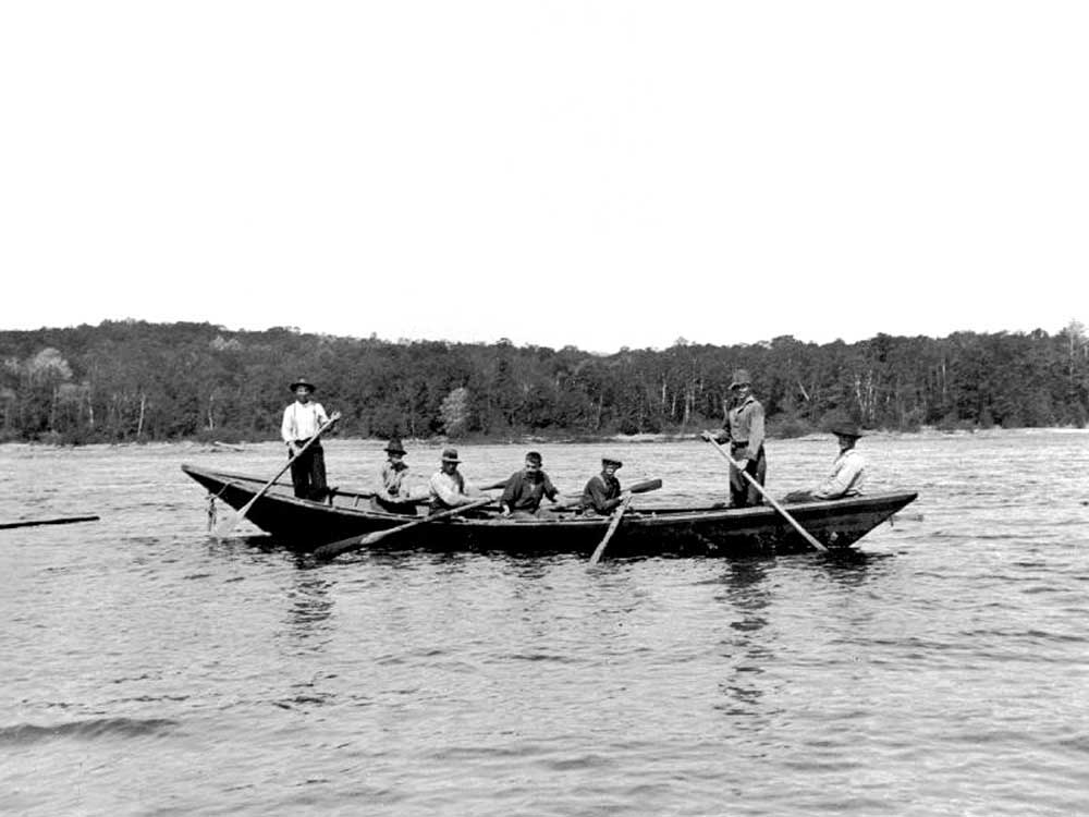 A pointer boat on the water, with six men on board.